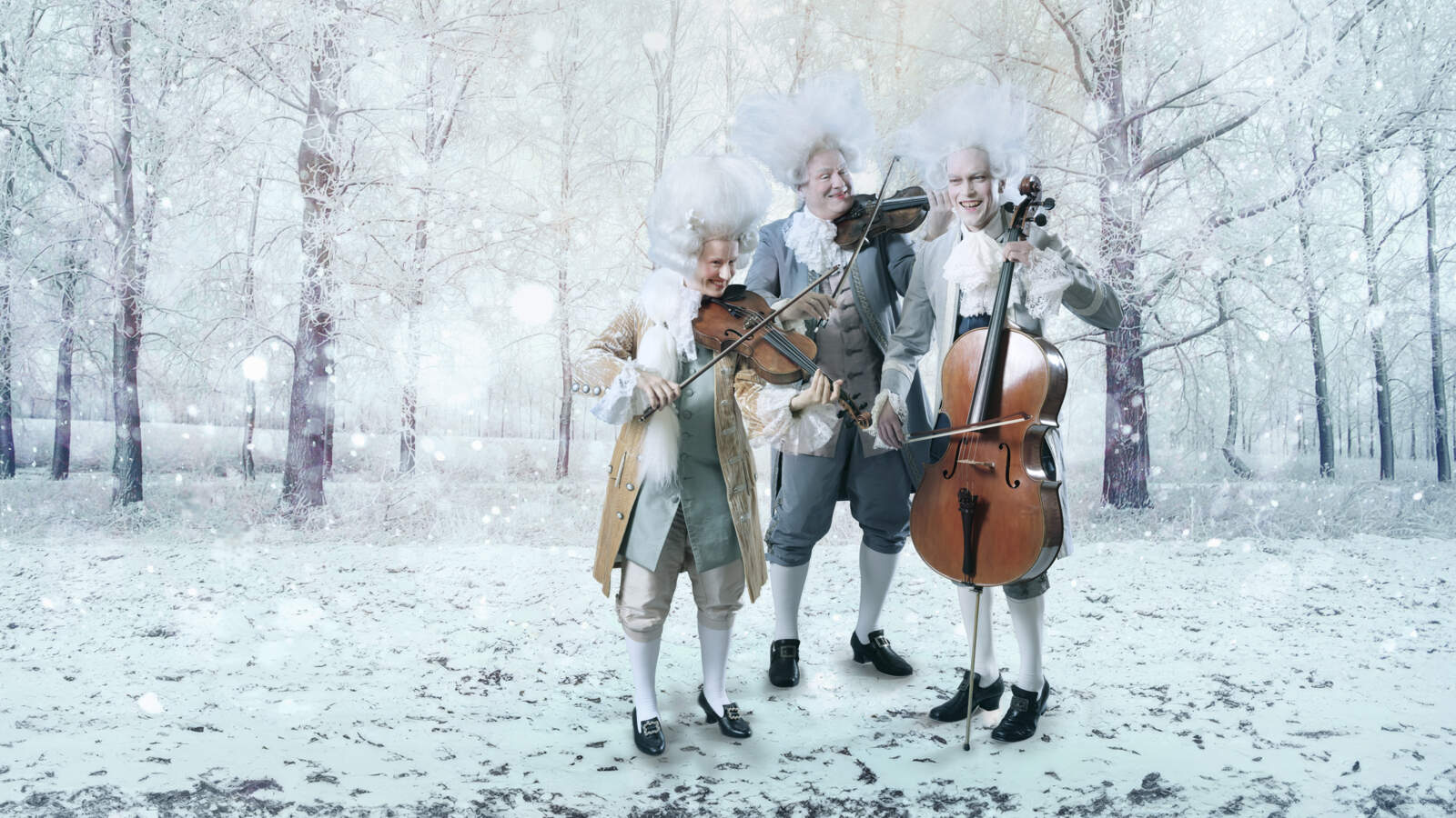 Tre stråkmusiker i barocka kläder och stora vita peruker står och spelar sina instrument på ett snöigt fält omringad av träd.