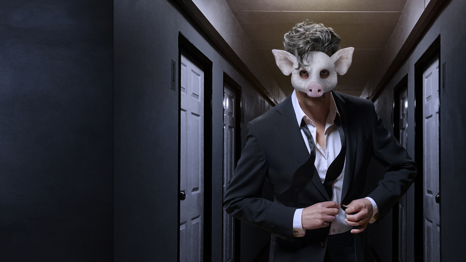 En man i kostym som bär en mask som ser ut som ett grishuvud står i en mörk hall.