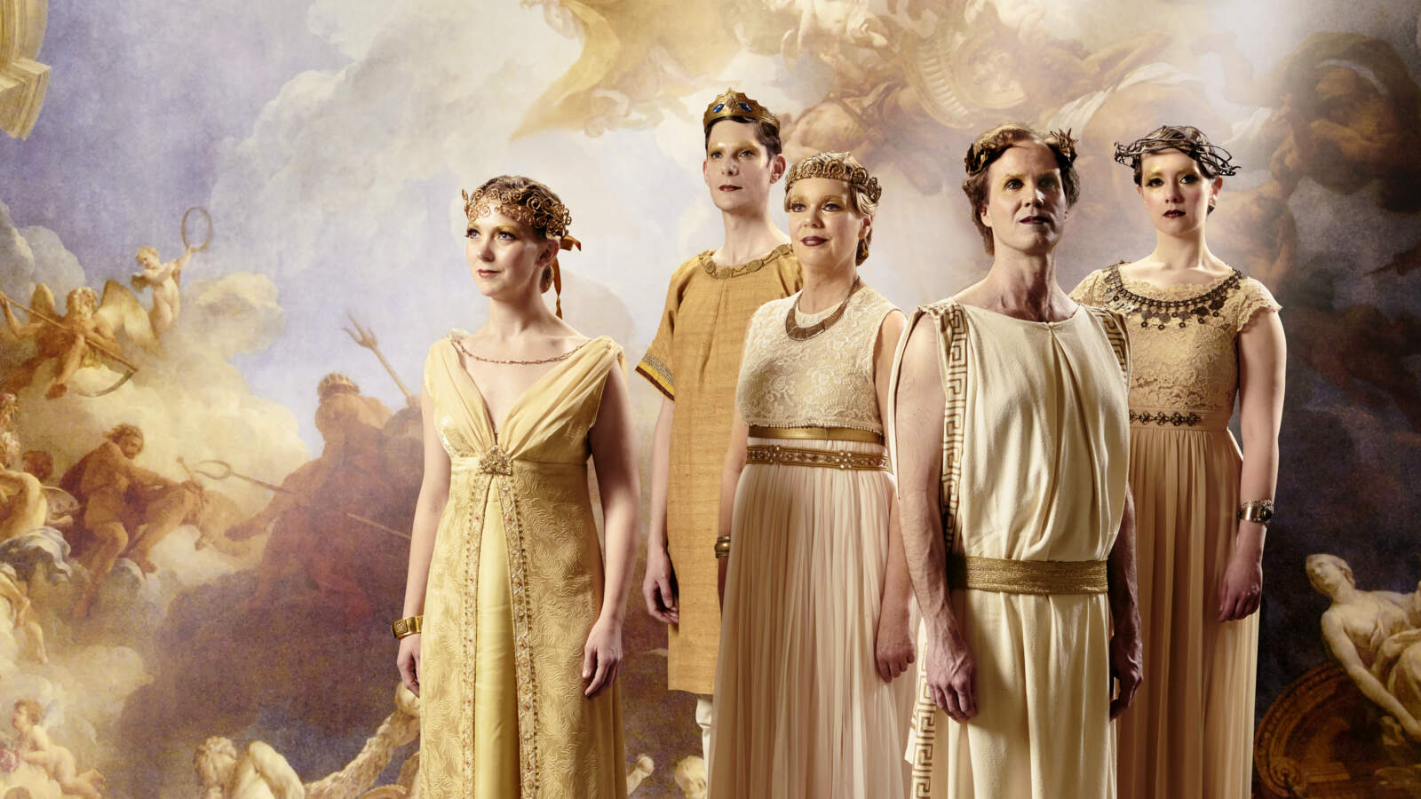 Fyra körsångare står framför en fond som visar ett målat renässanskyrktak. De bär gyllene diadem och tunikor i romersk stil.