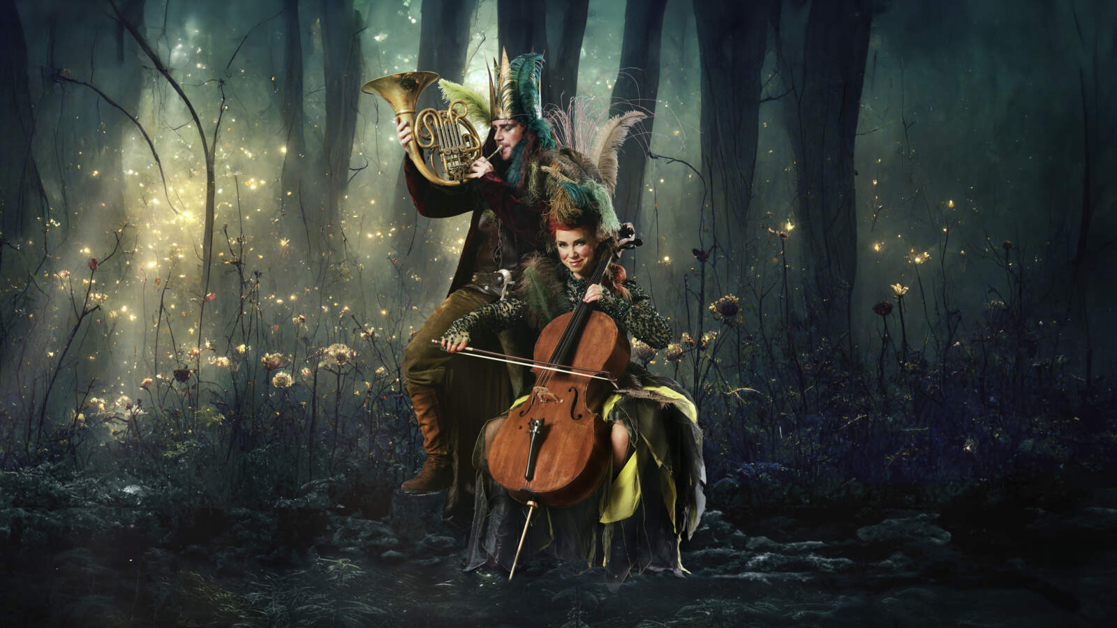 Två musiker som bär fantastiska kläder spelar sina instrument i en disig skog omgiven av brandlusar. Cellisten ler.