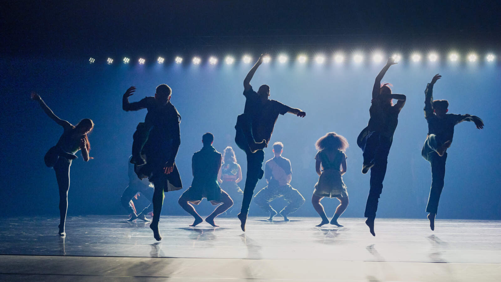 En grupp dansare dansar på en mörk scen.