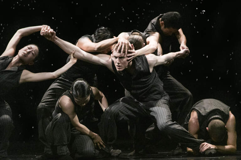 En grupp dansare dansar på en mörk scen